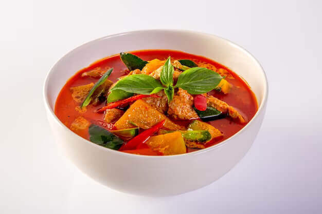 red curry pork vegetables panaeng white background